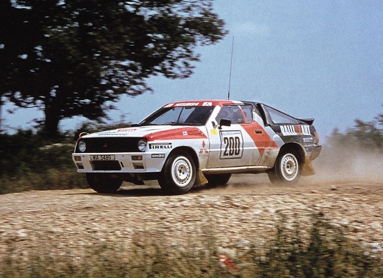 Rödvit rallybil med nummer 200 sladdar på en grusväg